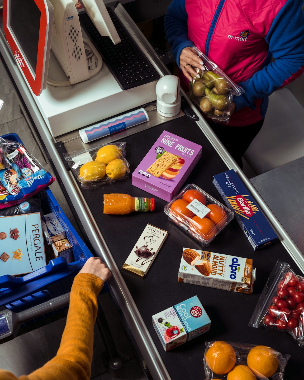 Müşteri, süpermarket kasasındaki konveyör bandına market ürünlerini yerleştiriyor.