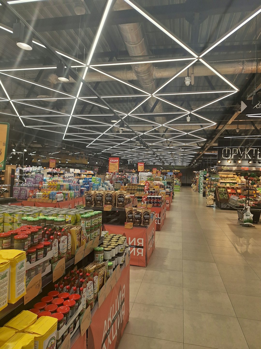 Modern bir süpermarket koridorunda düzenli bir şekilde stoklanmış bakkal rafları.