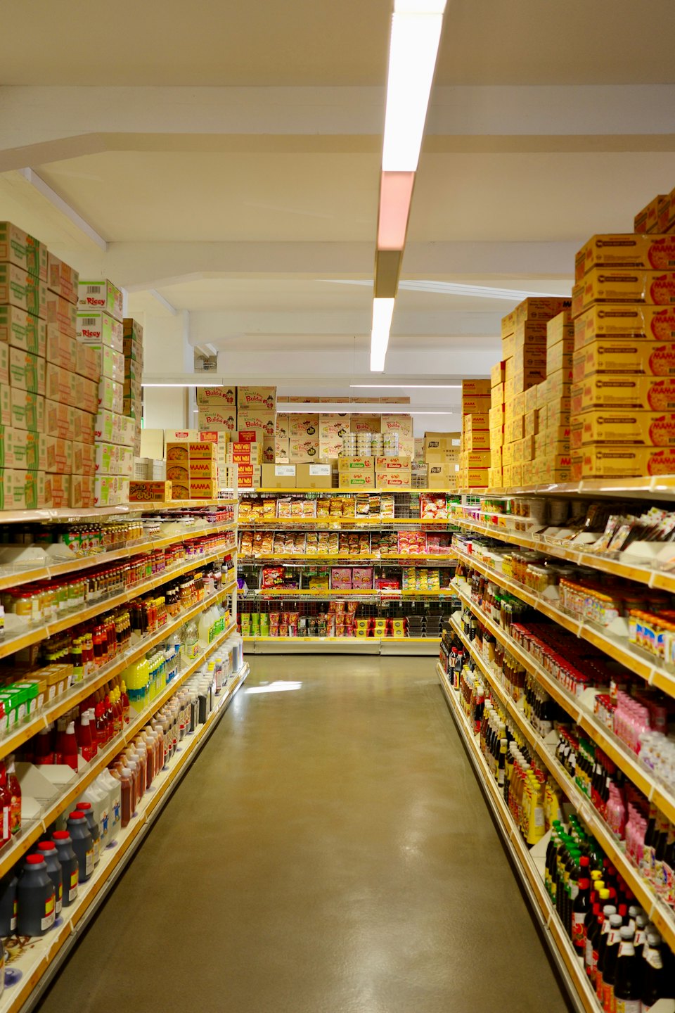 Yiyecek ürünleri ve kutularla dolu market koridoru.